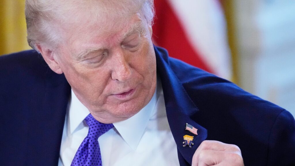 Trump models a ‘Happy Trump’ lapel pin at the White House